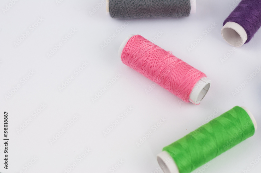 Scattered bobbins of new colorful threads on white background Scattered bobbins of new colorful threads on white background