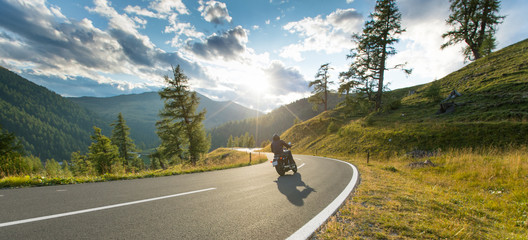 Motorcycle driver riding in Alpine highway, Nockalmstrasse, Austria, Europe.