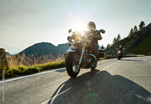 Fotografia Motorcycle driver riding japanese high power cruiser in Alpine highway on famous Hochalpenstrasse, Austria