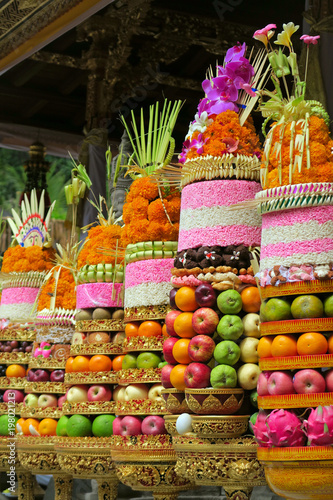 Fototapeta Naklejka Na Ścianę i Meble -  Traditional Balinese ceremonial temple offerings: big fruits and rice pyramids on golden plates decorated with flowers