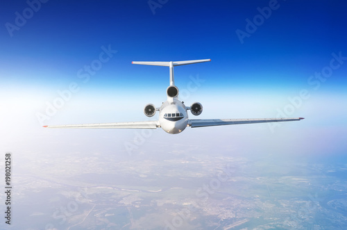 White airplane flies climbs height, flight level high in the sky above the clouds blue sky.