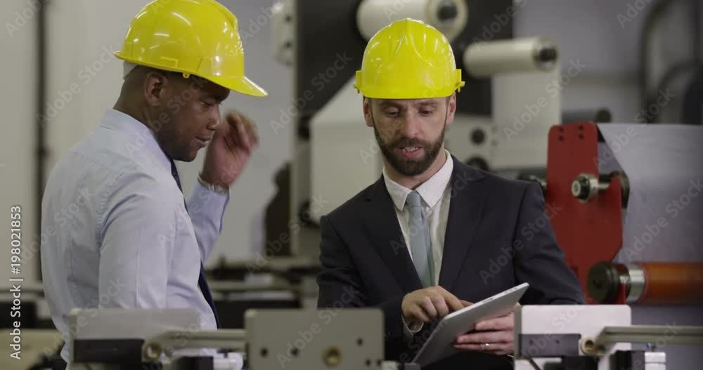 Manager discusses work with a factory worker on a digital tablet. Manager discusses work with a factory worker on a digital tablet.
