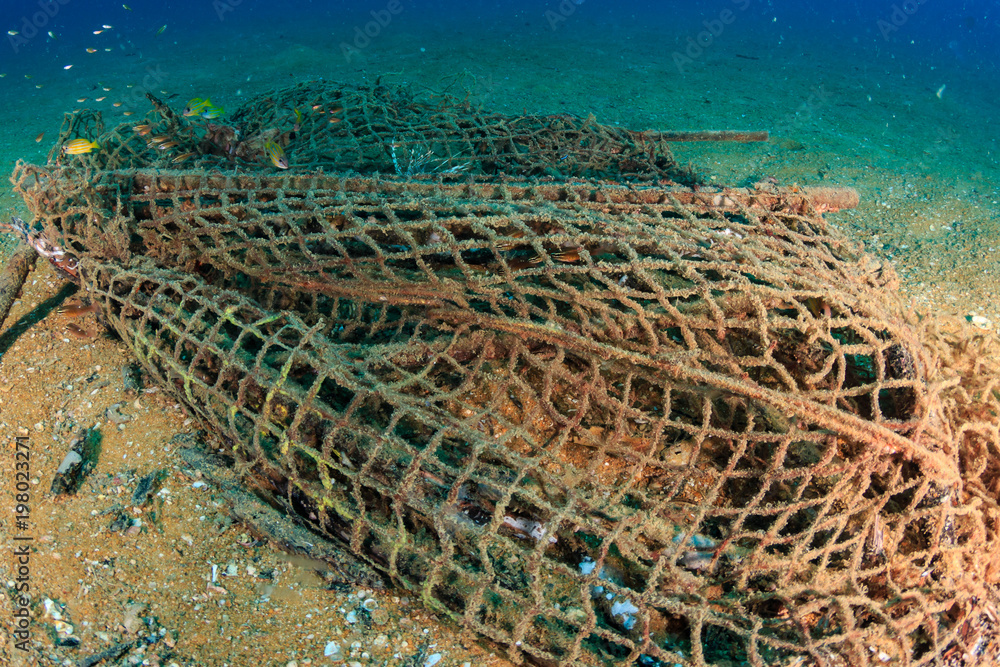 Pollution problem - Abandoned ghost fishing nets on the sea floor near a  tropical coral reef Stock Photo