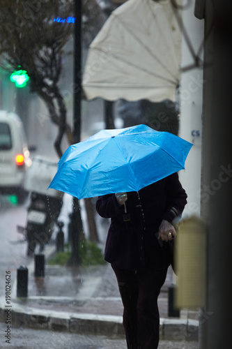 Woman in rain walking with umbrella.