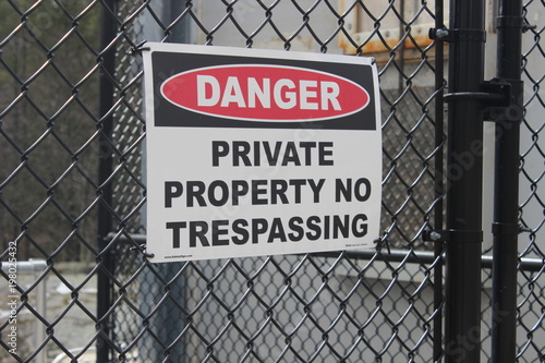 Danger private property sign on black fence at water dam 