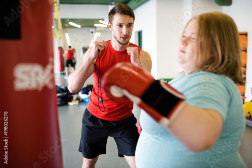 Portrait of young fitness instructor training obese young woman cheering during endurance practice