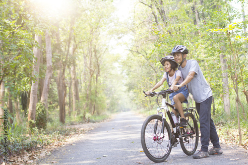 Happy father and daughter cycling in the park  togetherness relaxation concept
