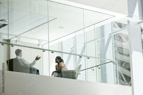 Businessman and woman behind conference room window in large business center