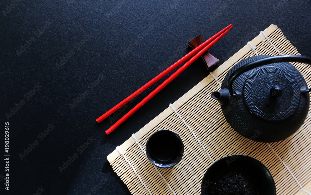 Red chopsticks and tea set Japanese on black table Top view with copy space Red chopsticks and tea set Japanese on black table Top view with copy space