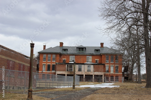 Old abandoned and boarded up brick asylum hospital building