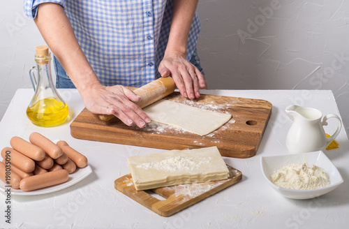 Home baking: a woman rolls the dough with a rolling pin.