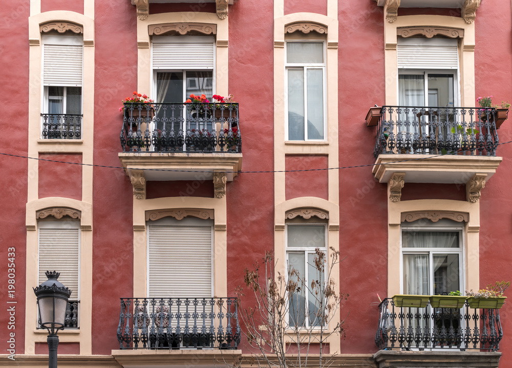 several windows of old apartment residential building of the early twentieth century red colorful facade at neighborhood, vintage apartment architecture