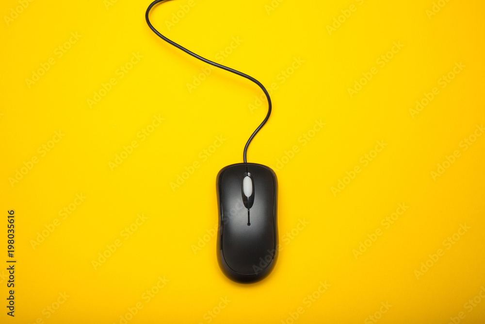 Black computer mouse on a yellow background. Black computer mouse on a yellow background.