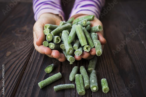 children's hands hold frozen green beans photo