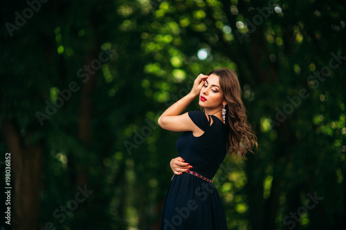 A beautiful girl in a blue dress is walking in the park.