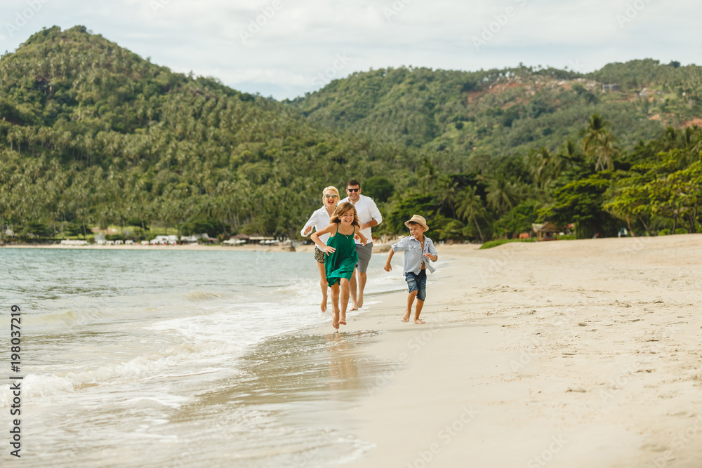 beautiful happy family running by beach on tropical island beautiful happy family running by beach on tropical island