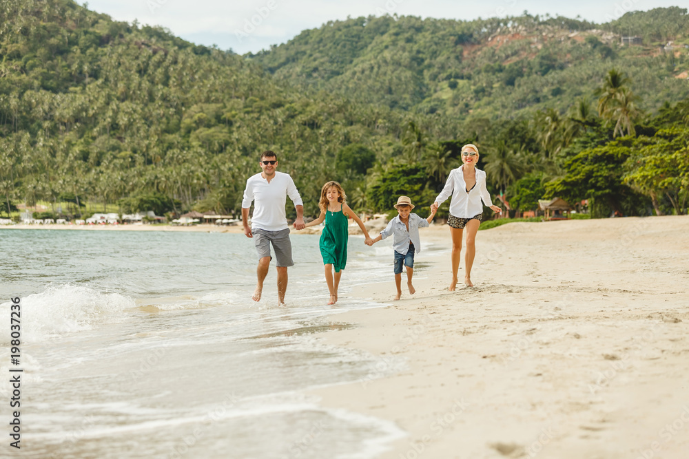 happy family on vacation running by beach on tropical island happy family on vacation running by beach on tropical island