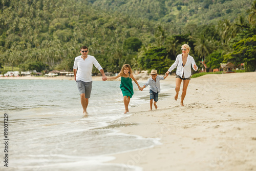 beautiful happy family running by beach and holding hands