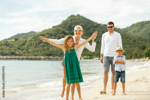 Bild auf Leinwand beautiful happy family posing on beach of tropical island