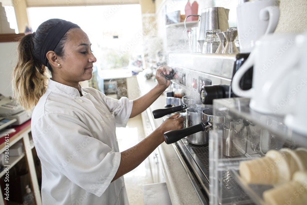 Woman using espresso machine in cafe