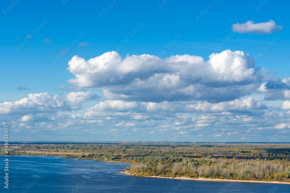 white clouds against the river and blue sky