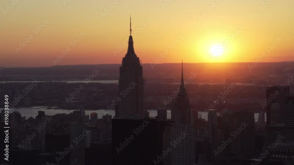 New York City aerial view from Midtown Manhattan with the sun setting over the Empire State Building and the Chrysler Building. New York City aerial view from Midtown Manhattan with the sun setting over the Empire State Building and the Chrysler Building.
