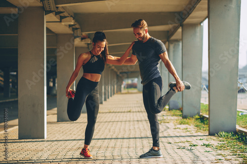 Young couple warming up in urban environment before jogging
