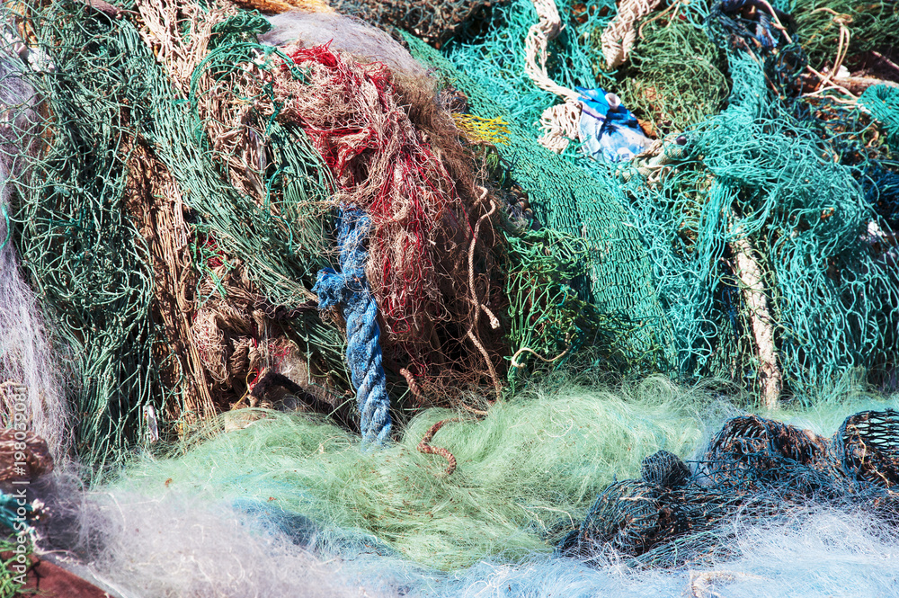 Pile of old and used fishing nets colored, floating and blue rope on the  quay, in very bad condition, waste from the sea. Gargano Coast, National  park on Puglia on Italy Stock