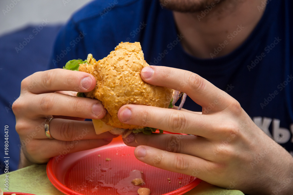 Close Up Of Man Hands Holding Delicious Burger and eating it Close Up Of Man Hands Holding Delicious Burger and eating it
