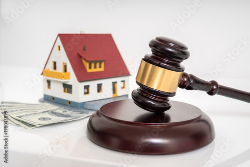 House auction concept. Gavel in front of model of house.