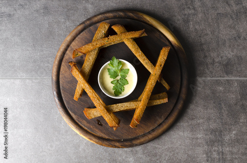 Crispy croutons with cheese sauce on a wooden plate photo