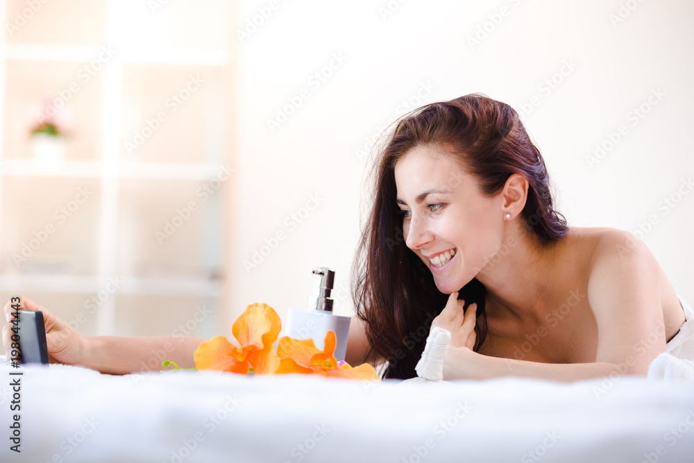 Beautiful young woman relaxing spa salon with selfi on mobile phone at spa resort Beautiful young woman relaxing spa salon with selfi on mobile phone at spa resort