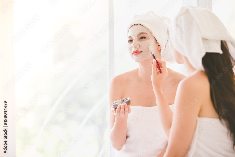 Beautiful young woman and friend spa applying cosmetic mask cream on face relaxing receiving massage,Spa face concept Beautiful young woman and friend spa applying cosmetic mask cream on face relaxing receiving massage,Spa face concept