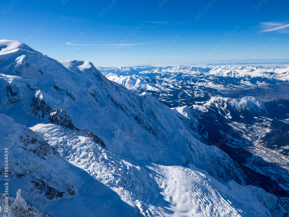 Snow slope with mountain against blue sky and steep peaks of the Alps, Mont Blanc, France.
