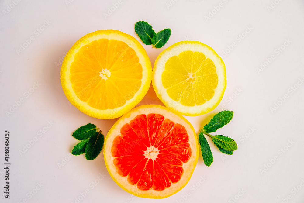 Slice of lemon, grapefruit, orange and mint leaves on a white background. Top feed Slice of lemon, grapefruit, orange and mint leaves on a white background. Top feed