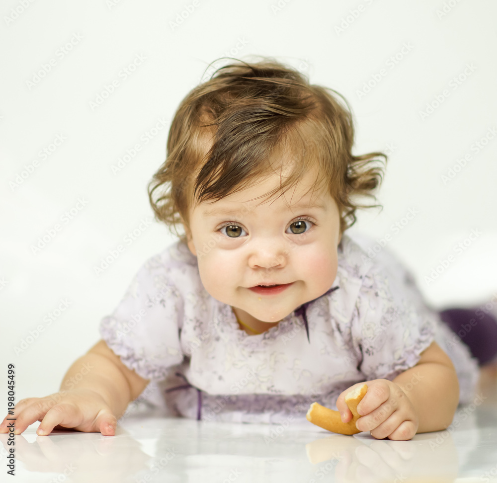 The little girl is eating a bagel. The concept of a healthy baby food. white background The little girl is eating a bagel. The concept of a healthy baby food. white background