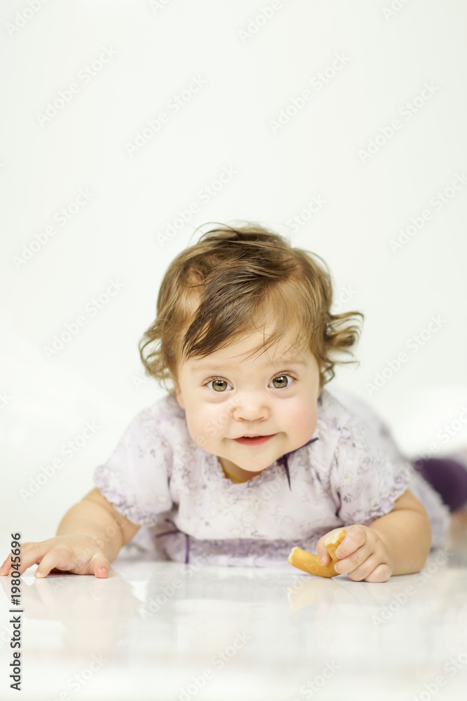 The little girl is eating a bagel. The concept of a healthy baby food. white background The little girl is eating a bagel. The concept of a healthy baby food. white background