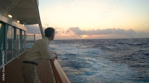 Single caucasian adult man looking at sunset from deck of cruise ship