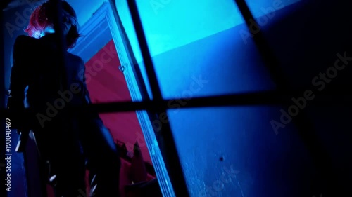 Danger killer woman with red hair walks down at stairs with gun at dark place