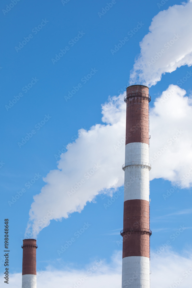 The steaming pipe of the plant or factory on the background of the blue sky. The steaming pipe of the plant or factory on the background of the blue sky.