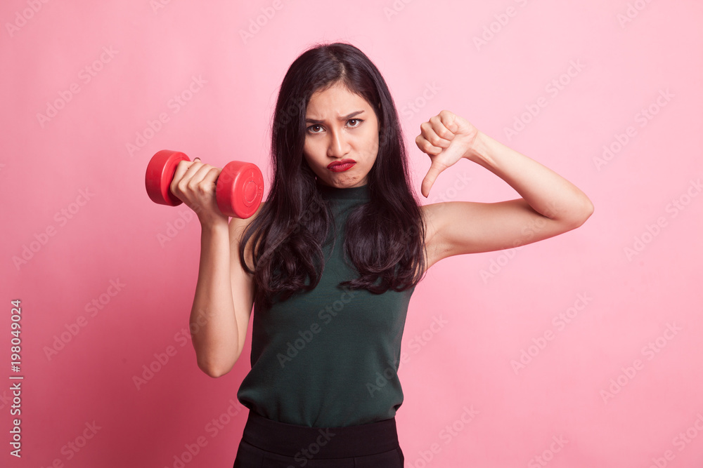 Unhappy Asian woman thumbs down with dumbbells. Unhappy Asian woman thumbs down with dumbbells.