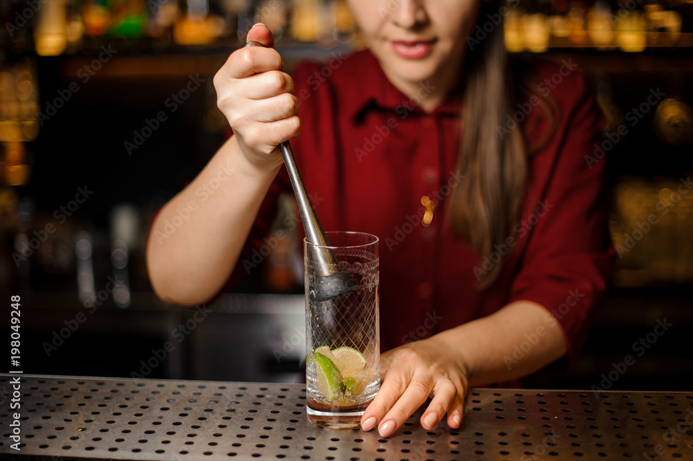 Female bartender pressing down a cane sugar with lime