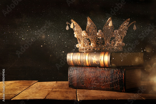 low key image of beautiful queen/king crown on old books. fantasy medieval period. Selective focus.