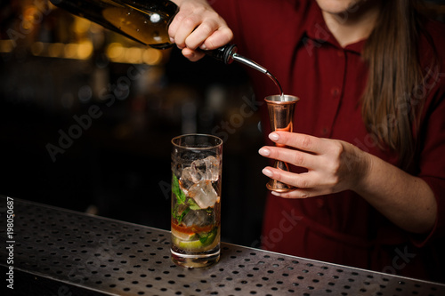 Female bartender filling a liqour to the measuring pile