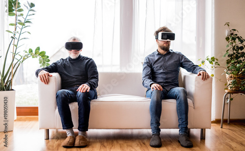 Hipster son and his senior father with VR goggles at home. © Halfpoint