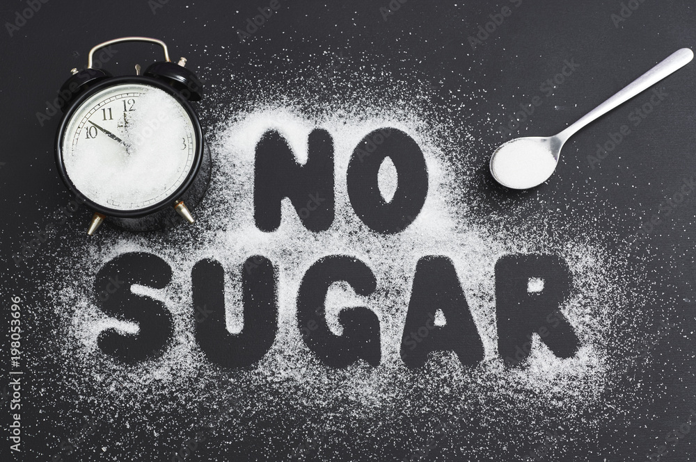 Spoonful of sugar and an alarm clock, covered with sugar on a dark table, sugar written the text 
