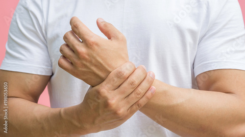 Men feeling pain in his wrist on a pink background.
