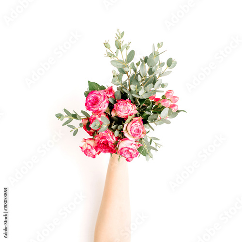 Flatlay of female hand hold rose flowers and eucalyptus bouquet on white background. Flat lay, top view spring blog hero header background.