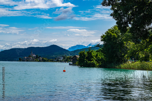 Austrian lakeside summer view from the forests' edge with mountains in the distance.