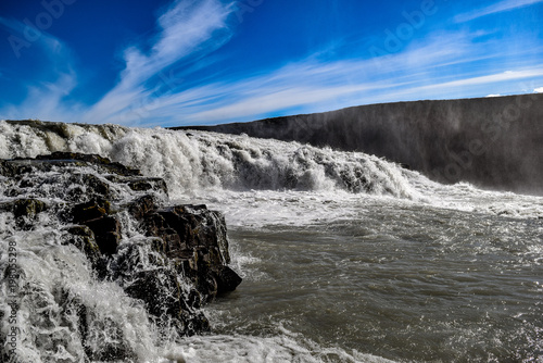 Raging waterfall in Iceland over volcanic rocks off of the glaciers